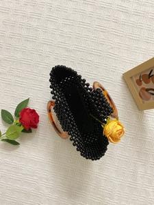 Bolso de cuentas negras hecho a mano con asas de acrílico ámbar sobre tela beige claro