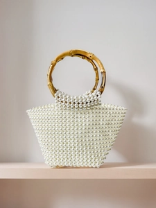 Macro shot of handcrafted pearl beaded handbag featuring a natural bamboo handle texture