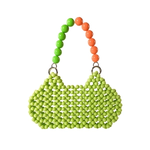 Detail of green acrylic beaded handbag with orange contrast handle and metal ring