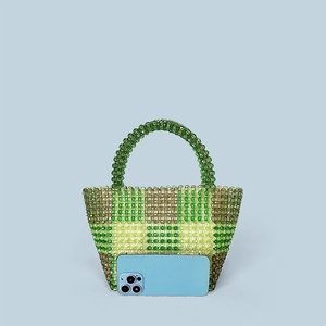 Detail of hand-woven beaded handbag with green checkered pattern and rounded handle