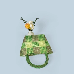 Detail shot of a handmade beaded checkered handbag in green and yellow on a blue base