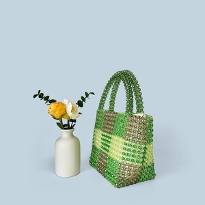 Detail of hand-woven beaded handbag featuring green and yellow checkered pattern beads