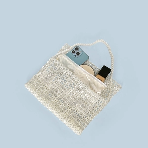 Detail of white handmade pearl woven tote bag showing internal capacity for phone and cosmetics