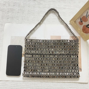 Close-up of metallic gunmetal beaded tote bag with shiny mirror finish on linen surface