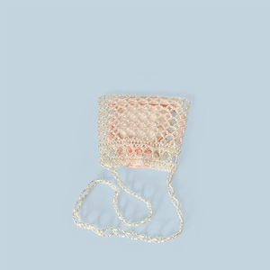 Detail of beaded mini bag with pink satin drawstring pouch and woven pearl texture