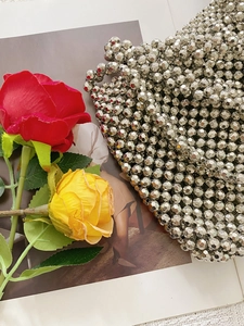 Close-up of handmade silver beaded crossbody bag with glossy metallic facets and chain