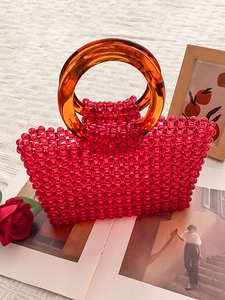 Sac à main fait main en perles rouges avec poignées en ambre sur fond blanc texturé
