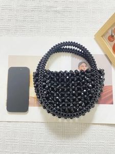 Vista dall'alto di una borsa nera con perline fatta a mano con smartphone per scala