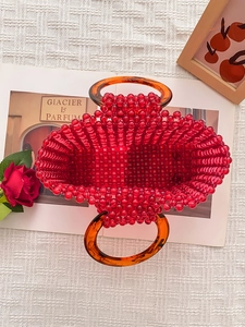 Sac à main artisanal en perles rouges avec anses anneaux en acrylique ambre sur fond blanc
