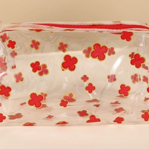 Close-up of clear PVC pencil case with red clover prints and a secure red zipper closure