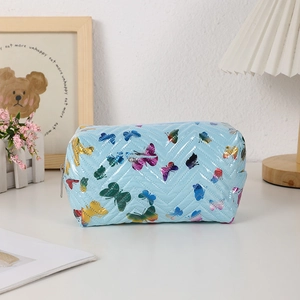 Detail of chevron quilted light blue makeup bag with vibrant butterfly print and zipper