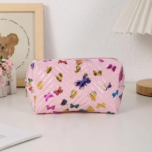 Macro detail of pink quilted makeup bag with butterfly print and smooth metal zipper
