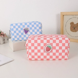 Detail of canvas makeup bags with checkered pattern and fruit embroidery patches