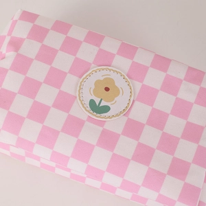 Close-up of pink checkered makeup bag showing textile texture and floral embroidery