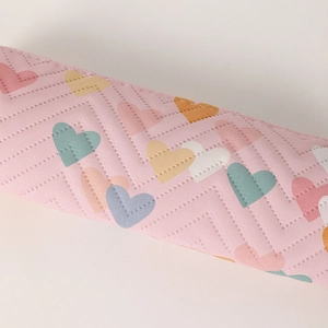 Close-up of quilted pink pencil case featuring colorful heart patterns and fine stitching