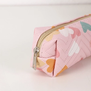 Detail of pink PU pencil case featuring V-shaped quilting and colorful heart patterns