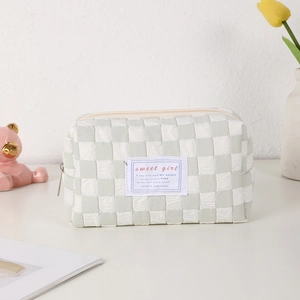 Detailed close-up of quilted checkerboard pouch with metal zipper and woven label