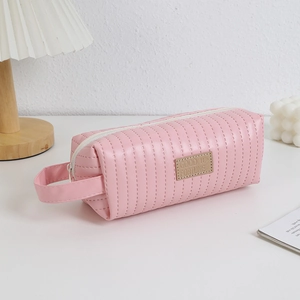 Detail of pink faux leather pencil case featuring vertical stitching and side handle strap
