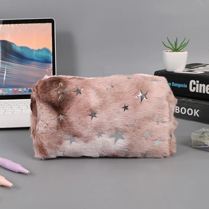 Detail of plush gradient pink pencil case with silver stars on a desktop setup