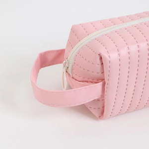 Detail of pink quilted PU pencil case featuring vertical stitching and a side handle