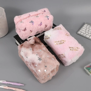 Three plush pencil cases in pink, gradient, and marble patterns on a desk setup