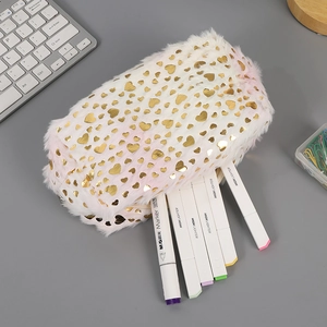 Detail of plush heart-patterned gradient stationery bag on desk with office supplies