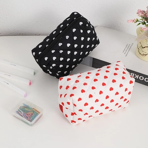 Quilted heart pattern makeup bags in black and white styles with zip closure on white desk