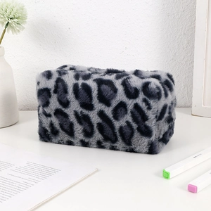 Detail view of the fuzzy leopard print makeup bag on a minimalist desktop with props