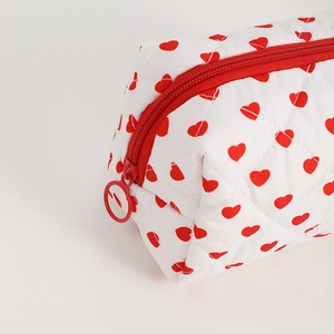 Detail of quilted heart pattern makeup bag with a red zipper and round metal puller