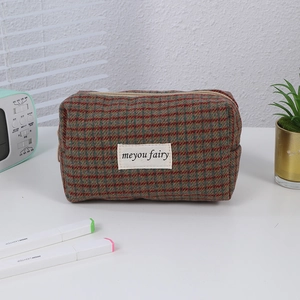 Close-up of checkered makeup bag in wool texture with woven label and metal zipper