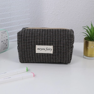 Detail of retro houndstooth makeup bag with metal zipper and minimalist fabric label