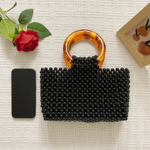 Détail du sac perlé avec poignées en acrylique ambre et smartphone pour échelle de taille