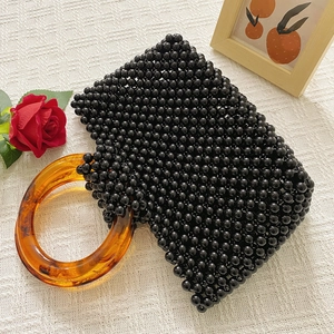 Vue rapprochée d'un sac à main en perles noires avec poignée en acrylique ambré chic