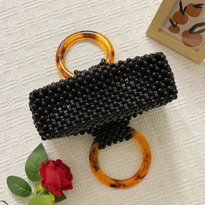 Vue détaillée du sac en perles noires avec poignées anneaux en résine ambrée écaillée
