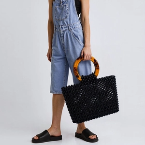 Détail du sac en perles noires tissées à la main avec grandes anses anneaux ambrés
