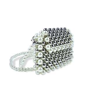Macro detail of hand-woven white pearls and silver beads on a vintage crossbody bag