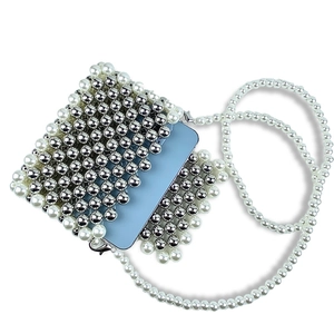 Detail of handmade woven crossbody bag with silver beads and white pearl shoulder strap