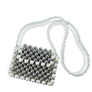 Detail of handmade beaded crossbody bag with woven white pearls and silver mirror beads
