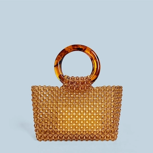 Détail du sac à main artisanal en perles ambrées avec de grandes poignées en anneau de résine
