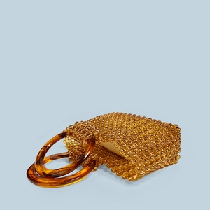 Détail d'un sac à main artisanal en perles ambrées transparentes avec poignées en résine