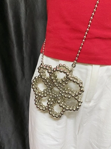 Silver flower-shaped beaded crossbody mini bag with metal spheres on a female model
