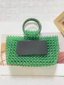Détail du sac à main vert perlé avec poignée anneau en résine marbrée et smartphone