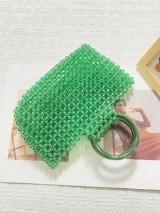 Gros plan d'un sac en perles acryliques vert herbe avec poignées rondes en résine sur tissu
