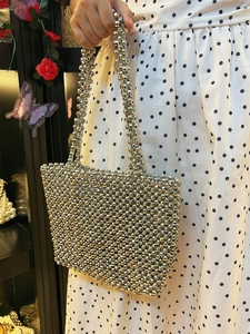 Détail d'un sac à main argenté montrant les perles métalliques et la texture tissée