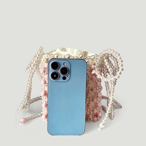 Détail du sac seau en perles roses et blanches montrant la taille avec smartphone