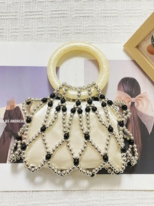 Detail of beaded handbag featuring a marble-textured resin ring handle and satin pouch