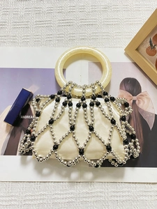 Close-up of handmade beaded bag with silver lattice design and cream round handle