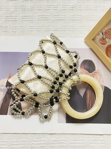 Detailed close-up of ivory satin handbag with silver and black beaded geometric mesh