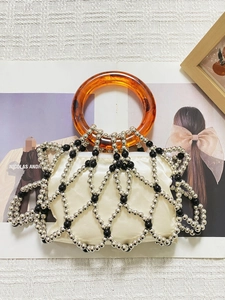 Close-up of vintage beaded handbag featuring amber acrylic handles and satin lining