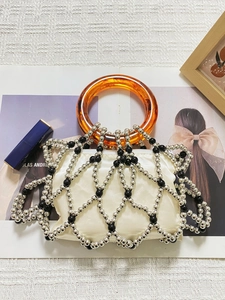 Detail of beaded handbag with amber resin ring handle and woven metallic lattice texture